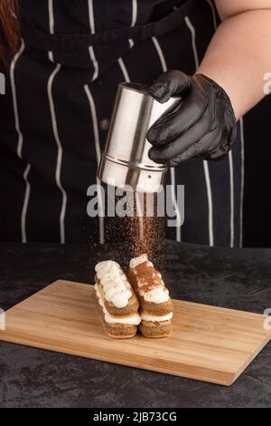 Herstellung von Tiramisu-Dessert-Kuchen auf dunklem Hintergrund in einem Café Stockfoto