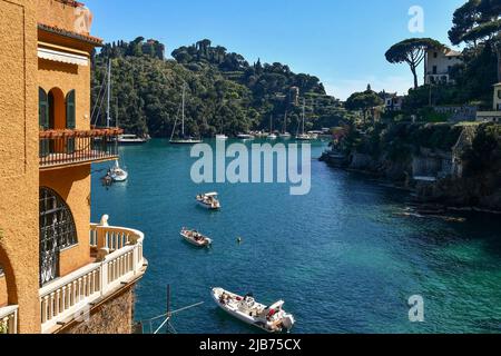 Bucht von Baia Cannone mit Sonnenbaden auf verankerten Booten, luxuriösen Villen am Meer und der Landzunge von Portofino im Hintergrund, Genua, Ligurien Stockfoto