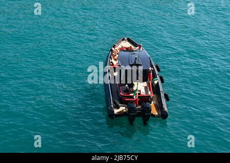 Blick auf Touristen, die sich auf einem Schnellboot sonnen, das in Baia Cannone, einer kleinen Bucht unweit des Zentrums von Portofino, Genua, vor Anker liegt Stockfoto