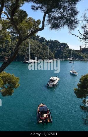 Bucht von Baia Cannone mit Sonnenbaden auf verankerten Booten und der Landzunge von Portofino im Hintergrund, Genua, Ligurien Stockfoto
