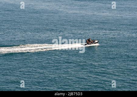 Drei Personen fahren auf einem einzigen Jet-Ski im Meer vor der Küste von Portofino, Genua, Ligurien, Italien Stockfoto