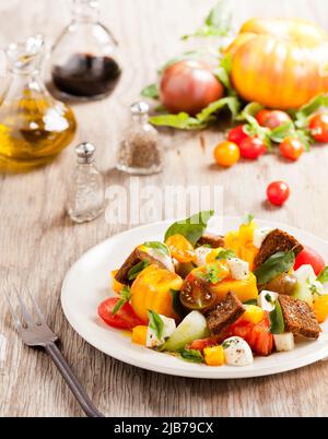 Ein frischer Caprese Tomatensalat mit Öl und Essig auf Holzplatte Stockfoto