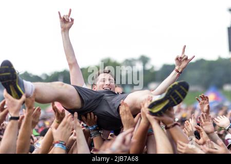 Nürnberg, Deutschland. 03.. Juni 2022. Beim Open-Air-Festival 'Rock im Park' lässt sich ein Besucher über die Menge hinwegtragen. Es ist eines der größten Musikfestivals in Bayern. In den vergangenen Jahren waren bis zu 70.000 Rockfans gekommen. Das Festival dauert bis zum 5. Juni. Quelle: Daniel Karmann/dpa/Alamy Live News Stockfoto