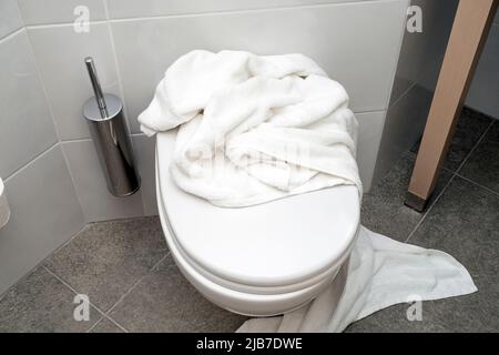 Ich habe ein weißes Handtuch auf der Toilette im Hotelbadezimmer liegen lassen Stockfoto