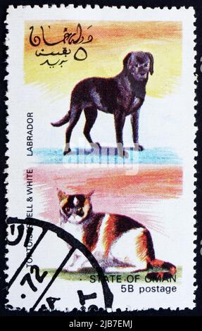 OMAN - UM 1972: Eine im Oman gedruckte Marke zeigt Tortoiseshell und White Cat und Labrador Dog, um 1972 Stockfoto