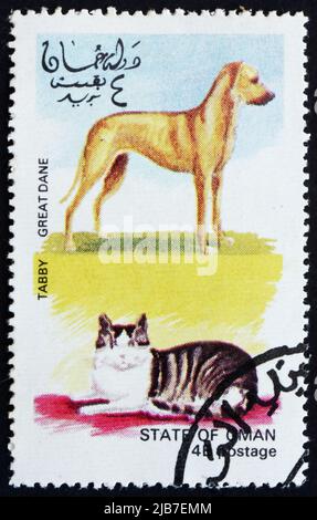OMAN - UM 1972: Eine im Oman gedruckte Briefmarke zeigt Tabby Cat und Great Dane Dog, um 1972 Stockfoto