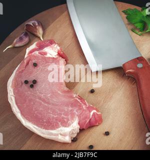 Auswahl an rohen Rindersteaks zum Grillen auf Küchenbrettchen mit Zutaten zum Kochen Stockfoto