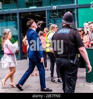 Epson Surrey, London, Großbritannien, 03 2022. Juni, Polizeibeamter, der jungen Mann beim Alkoholtrinken auf der Straße vor dem Bahnhof Epsom beobachtet Stockfoto