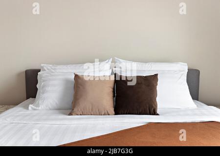 Viele weiche Kissen auf einem komfortablen Bett im Innenbereich Stockfoto