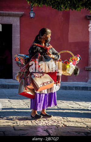 Eine indigene Frau, die auf dem Hauptplatz von San Miguel de Allende, Mexiko, eine Vielzahl mexikanischer Volkskunst verkauft. Stockfoto