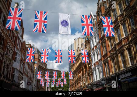 Über einer Straße im Zentrum londons hängt ein buntes Bündnis mit der Gewerkschaftsflagge, um das Platin-Jubiläum der Königin zu feiern (70 Jahre). Stockfoto