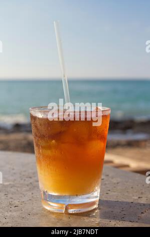 Eiskalter und erfrischender Mai Tai Cocktail in einem Glas an einem tropischen Strand mit Blick auf das Meer, an einem sonnigen Tag. Stockfoto