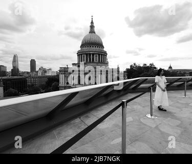 London, Greater London, England, Mai 21 2022: Blick von One New Change in Richtung St. Pauls Cathedral. Eine asiatische Dame in einem weißen Kleid posiert für ein Foto. Stockfoto