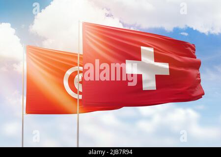 Sonniger blauer Himmel und Flaggen der schweiz und tunesiens Stockfoto