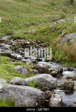 Abfluss-Wasser fließt über Felsen und Felsbrocken in einem Bergpass in den Brecon Beacons, South Wales. Stockfoto