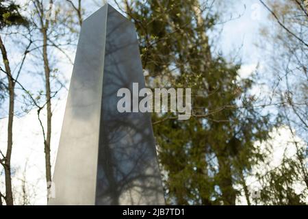 Obelisk aus Granit vor Waldgrund. Ort des militärischen Ruhms. Denkmal für Soldaten. Details des Denkmals, wo unbekannte Soldaten des zweiten W Stockfoto