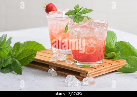 Kalter Sommer Erdbeer Eiscocktail Mojito, margarita, Daiquiri in zwei Gläsern mit Minzblättern auf hellem Hintergrund Stockfoto