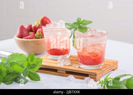 Kalter Sommer Erdbeer Eiscocktail Mojito, margarita, Daiquiri in zwei Gläsern mit Minzblättern auf hellem Hintergrund Stockfoto