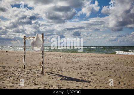 Wunderschöne Wolken und ein windiges Hochzeits-Baldachin am Sandstrand. Hochzeitszeremonie am Strand Stockfoto