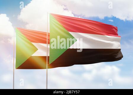 Sonniger blauer Himmel und Flaggen des sudan und des sudan Stockfoto