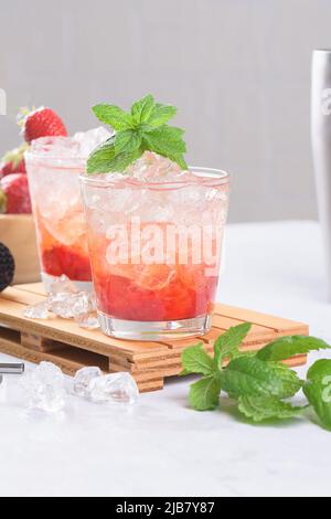 Kalter Sommer Erdbeer Eiscocktail Mojito, margarita, Daiquiri in zwei Gläsern mit Minzblättern auf hellem Hintergrund Stockfoto