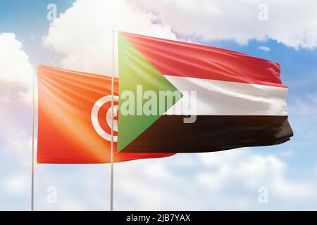 Sonniger blauer Himmel und Flaggen des sudan und tunesiens Stockfoto