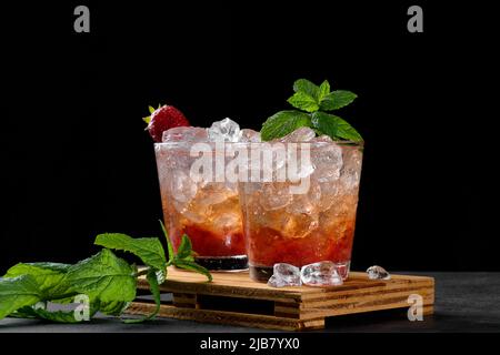 Kalter Sommer Erdbeer Eiscocktail Mojito, margarita, Daiquiri in zwei Gläsern mit Minzblättern auf dunklem Grund Stockfoto