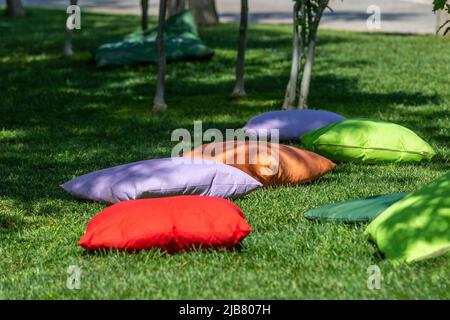 Studenten sitzen auf Kissen unter Bäumen Stockfoto