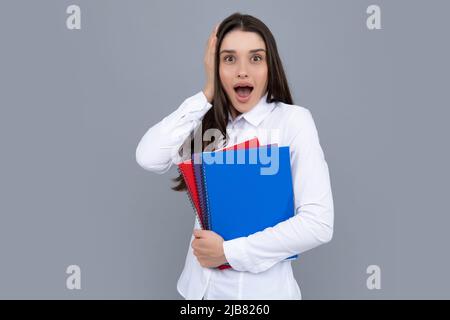 Teen Mädchen mit Notizbüchern stehen auf grauem Hintergrund mit Kopieplatz. Pädagogisches Konzept für die Schule. Porträt eines jungen Studenten. Stockfoto