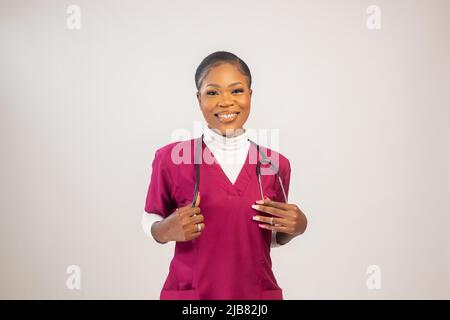 Covid-19, Mitarbeiter im Gesundheitswesen, Pandemiekonzept. Porträt einer selbstbewussten lächelnden, attraktiven asiatischen Krankenschwester in Scrubs, mit Stethoskop. Stockfoto