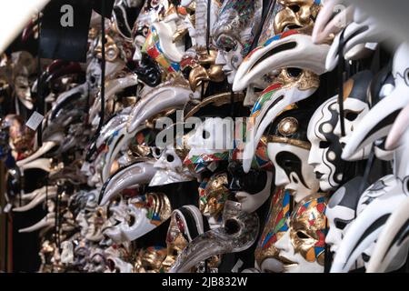 Venedig, Italien - 18.02.2022: Eine Nahaufnahme von Dutzenden von bunten traditionellen venezianischen Karnevalsmasken, die in einem Maskengeschäft in Venedig, Italien, an einer Wand hängen Stockfoto