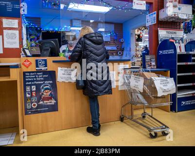 Kirkland, WA USA - ca. Dezember 2021: Schräge Ansicht einer Person, die während der Weihnachtszeit ein Paket bei einem USPS verschiffen hat Stockfoto