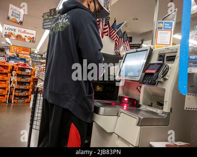 Kirkland, WA USA - ca. September 2021: Schräge Ansicht eines Mannes mit Gesichtsmaske, der an einem Selbstbedienungsautomaten in einem QFC-Lebensmittelgeschäft auscheckt. Stockfoto