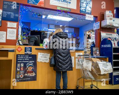 Kirkland, WA USA - ca. Dezember 2021: Schräge Ansicht einer Person, die während der Weihnachtszeit ein Paket bei einem USPS verschiffen hat Stockfoto