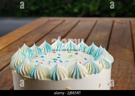 Nahaufnahme der Oberseite des Vanillekuchen mit Buttercreme-Zuckerguss. Garten im Hintergrund. Stockfoto
