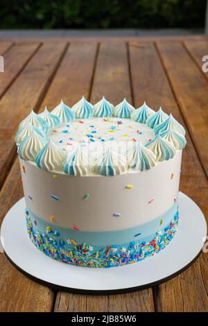 Nahaufnahme der Oberseite des Vanillekuchen mit Buttercreme-Zuckerguss. Garten im Hintergrund vertikal. Stockfoto