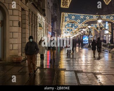 Bild eines weißen kaukasischen Mannes in belgrad, serbien, der in der Nacht, während der weihnachtszeit, mit Illuminationen in den Straßen von Belgrad spazierend ist, während w Stockfoto