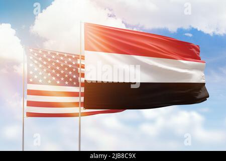 Sonniger blauer Himmel und Flaggen des jemen und der usa Stockfoto