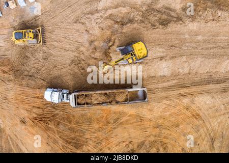 Vorbereiten Land für die Baustelle Bagger LKW laden Boden ein Muldenkipper Stockfoto