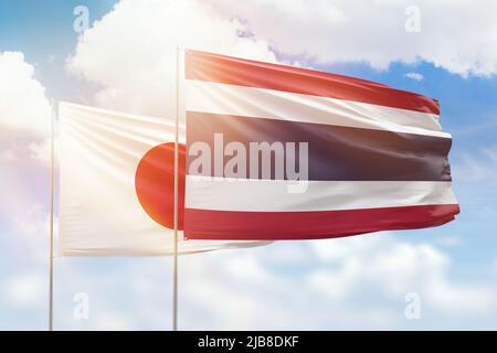 Sonniger blauer Himmel und Flaggen von thailand und japan Stockfoto