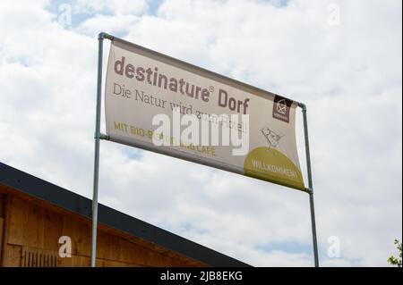 Hitzacker, Deutschland. 03.. Mai 2022. 'Destinature Village' ist auf einem Banner geschrieben. Mini-Holzchalets laden zum Übernachten ein, und ein Wellnessbereich mit Sauna lädt zum Entspannen ein. Das Destinature Village erhielt dafür den Deutschen Tourismuspreis. (To dpa: Glamping in Hütten auf Stelzen im Destinature Village Hitzacker) Quelle: Philipp Schulze/dpa/Alamy Live News Stockfoto