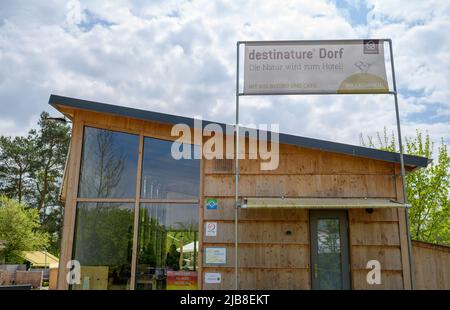 Hitzacker, Deutschland. 03.. Mai 2022. 'Destinature Village' ist auf einem Banner geschrieben. Mini-Holzchalets laden zum Übernachten ein, und ein Wellnessbereich mit Sauna lädt zum Entspannen ein. Das Destinature Village erhielt dafür den Deutschen Tourismuspreis. (To dpa: Glamping in Hütten auf Stelzen im Destinature Village Hitzacker) Quelle: Philipp Schulze/dpa/Alamy Live News Stockfoto