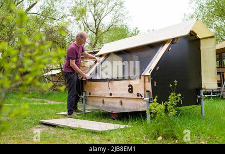 Hitzacker, Deutschland. 03.. Mai 2022. Holger Danneberg, Schöpfer und Besitzer des Schicksaldorfes, steht an einem "bed to go" im Schicksaldorf. Mini-Holzhäuser laden zum Übernachten ein, und ein Wellnessbereich mit Sauna lädt zum Entspannen ein. Dafür erhielt das Zieldorf den Deutschen Tourismuspreis. (To dpa: Glamping in Hütten auf Stelzen im Destinature-Dorf Hitzacker) Quelle: Philipp Schulze/dpa/Alamy Live News Stockfoto