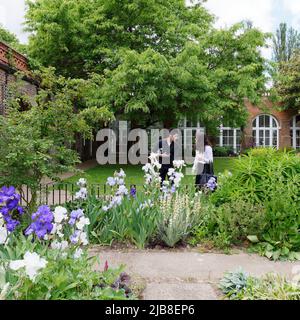 London, Greater London, England, Mai 28 2022: Paare betrachten die Blumen im begrünten Garten mit der Orangerie im Holland Park in Kensington. Stockfoto