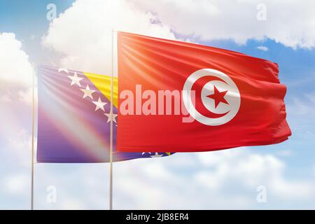 Sonniger blauer Himmel und Flaggen von tunesien und bosnien Stockfoto