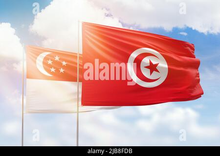 Sonniger blauer Himmel und Flaggen von tunesien und singapur Stockfoto