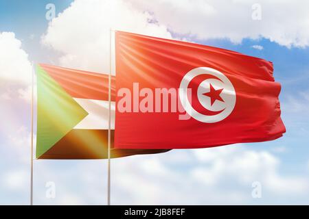 Sonniger blauer Himmel und Flaggen von tunesien und sudan Stockfoto