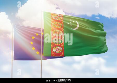 Sonniger blauer Himmel und Flaggen von turkmenistan und der europäischen Union Stockfoto