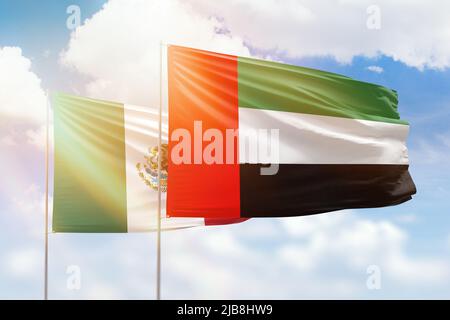 Sonniger blauer Himmel und Flaggen der vereinigten arabischen emirate und mexikos Stockfoto