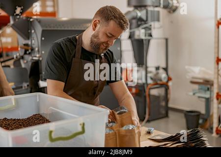 Unternehmer in Uniform-Packs geröstete Kaffeebohnen in Verpackungen zum Verkauf Stockfoto
